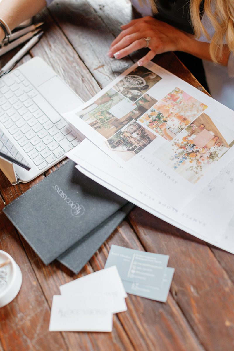 Upstate NY wedding planner reviews a mood board and sample floor plan beside a laptop and KR Occasions business cards, part of the design process when hiring a wedding planner.