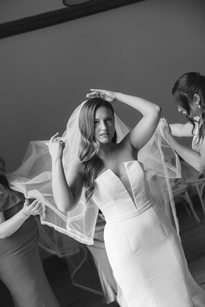Bride adjusts her veil with bridesmaids’ help before the ceremony.