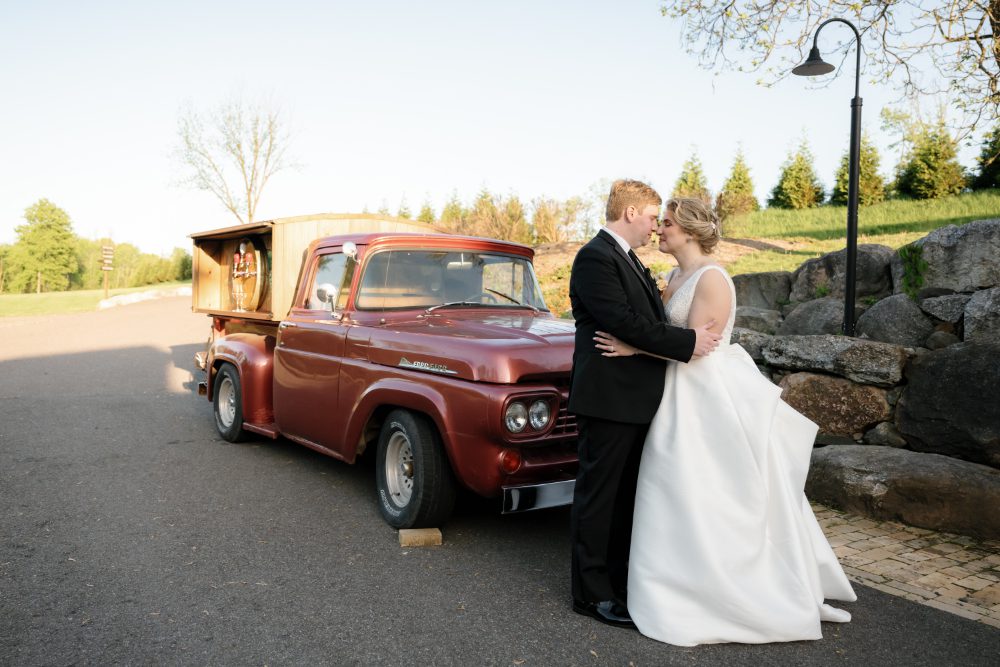 outdoor wedding portrait of bride and groom standing in front of an old red truck