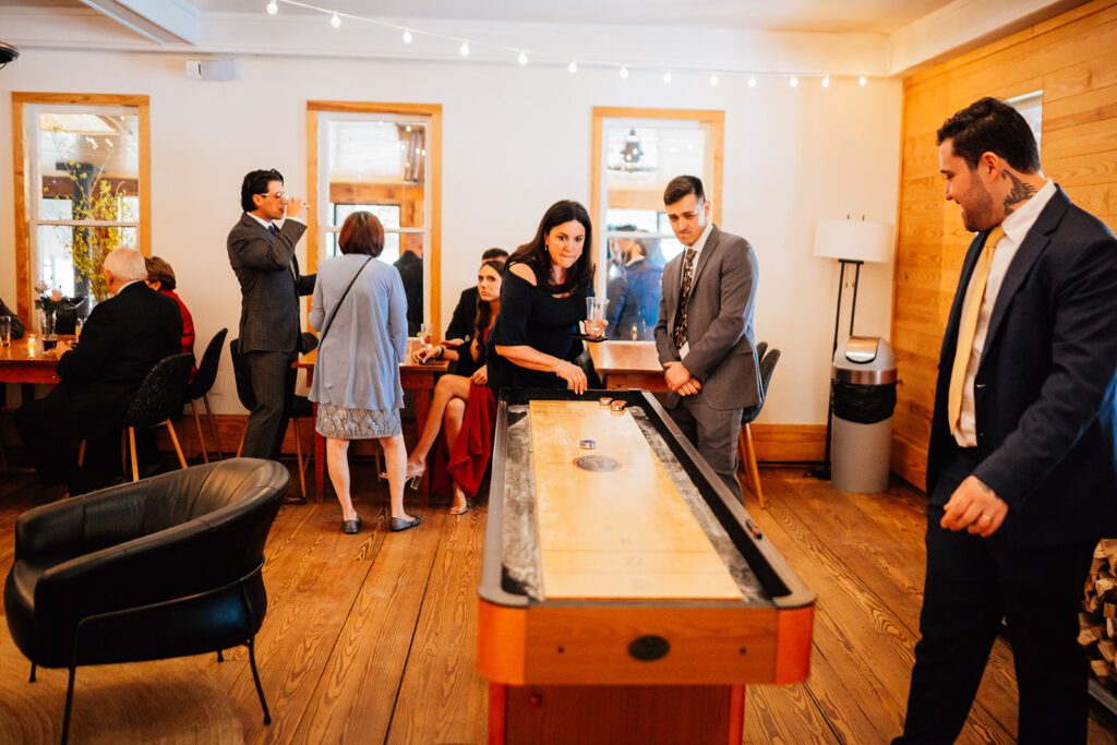 Guests play shuffleboard while others talk and drink in a lounge at The Arnold House.
