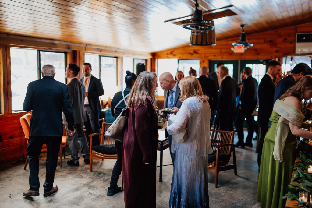 Groups of guests chat and enjoy drinks inside the cozy wooden lounge at The Arnold House.