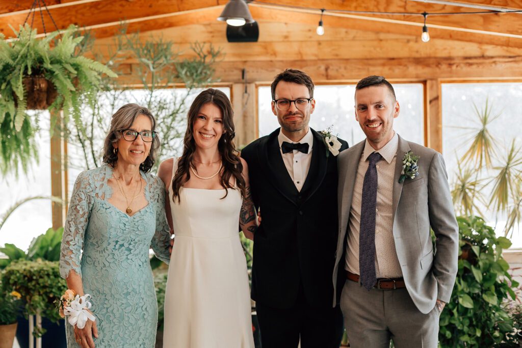 Bride and groom pose with family indoors at The Arnold House, surrounded by greenery.