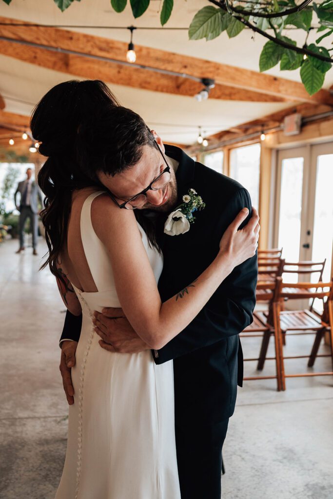 Groom closes his eyes, smiling as he embraces the bride during their first look.