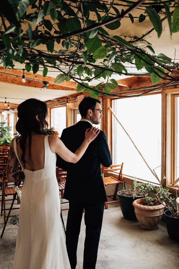 Bride taps the groom’s shoulder during their first look inside The Arnold House.
