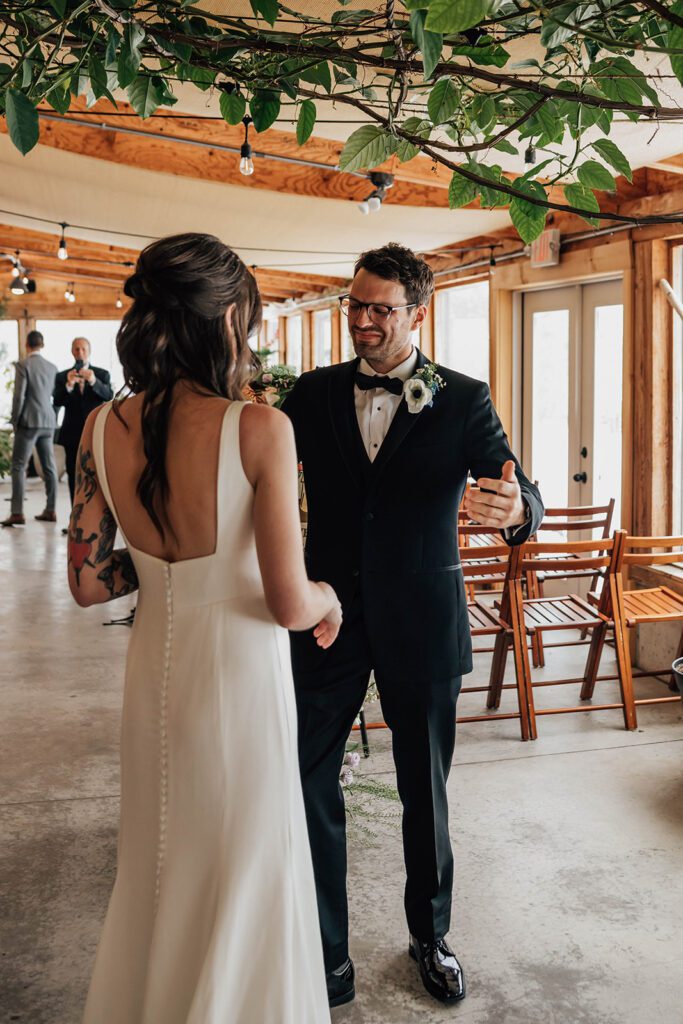 Groom reacts emotionally, reaching to embrace the bride during their first look.