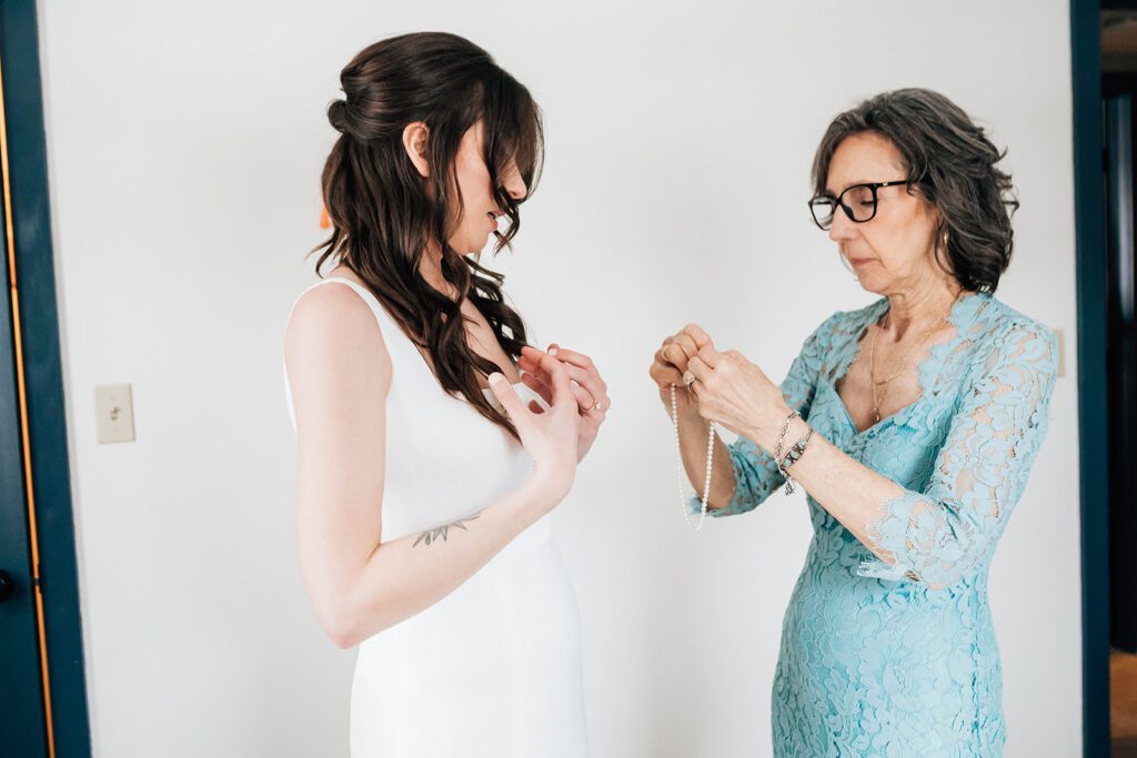Bride’s mother helps her with a pearl necklace before the ceremony at The Arnold House.