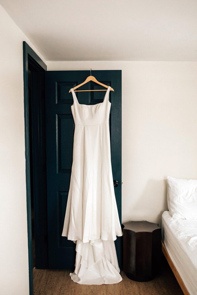 A white wedding dress hangs neatly on a dark door at The Arnold House.