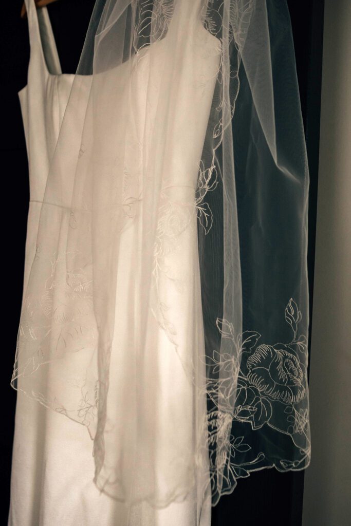 Close-up of the wedding dress and embroidered veil hanging at The Arnold House.