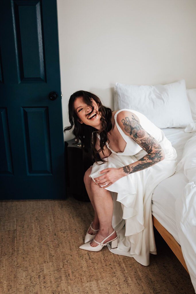 Bride laughs as she puts on her wedding shoes.