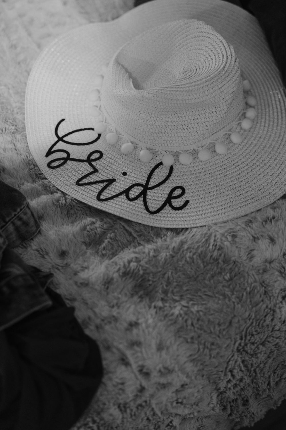 BLACK AND WHITE CLOSE UP OF A SUN HAT WITH "BRIDE" EMBROIDERED INTO IT.