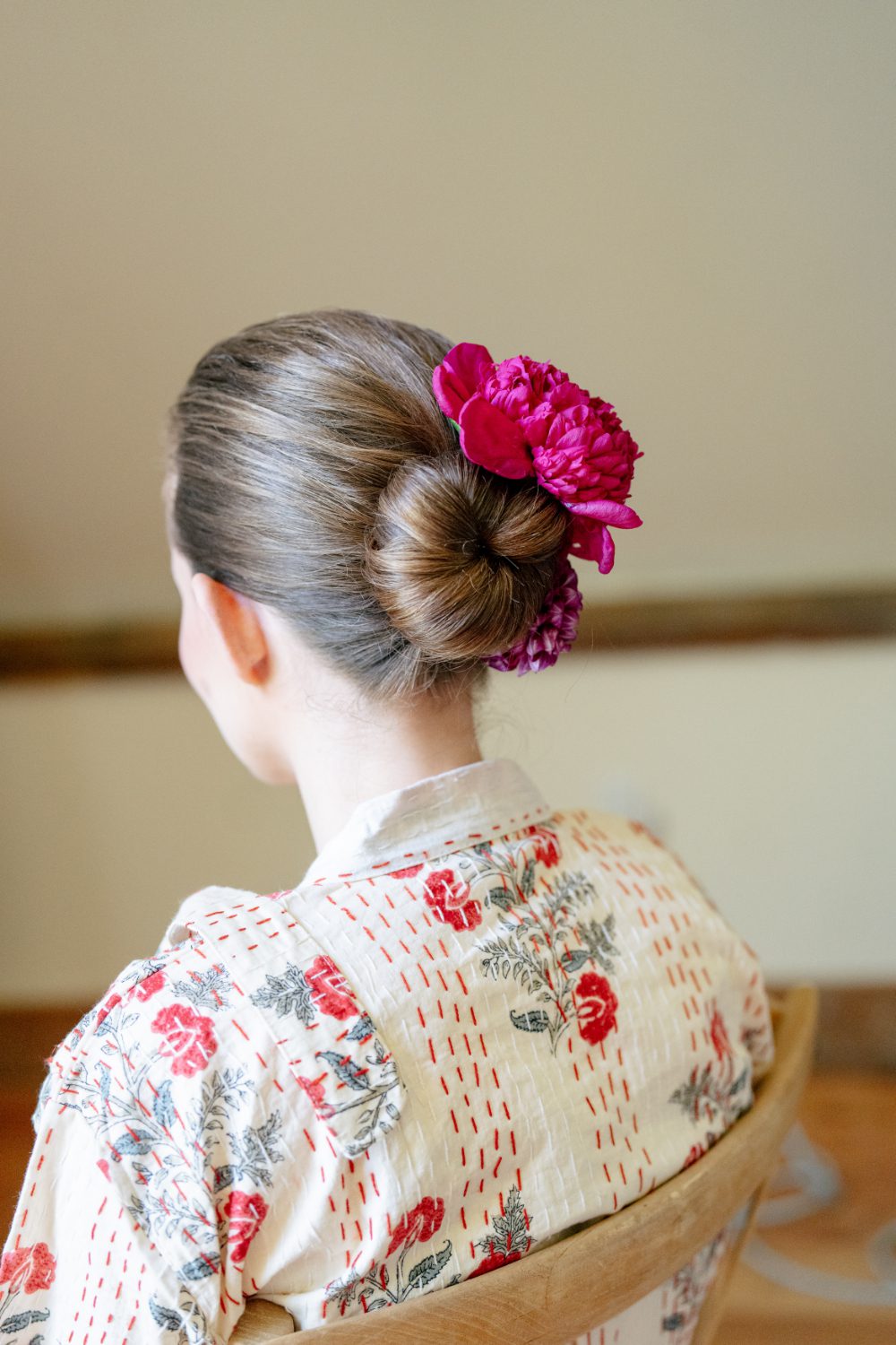 CLOSE UP OF BRIDES HAIR PINNED IN A BUN AND A DEEP MAGENTA FLOWER