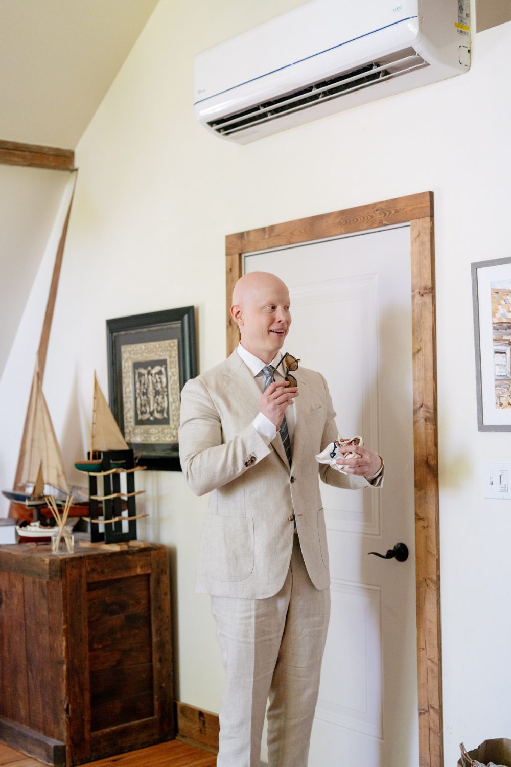 GROOM GETTING READY FOR WEDDING IN LIGHT LINEN SUIT AND STRIPED TIE.