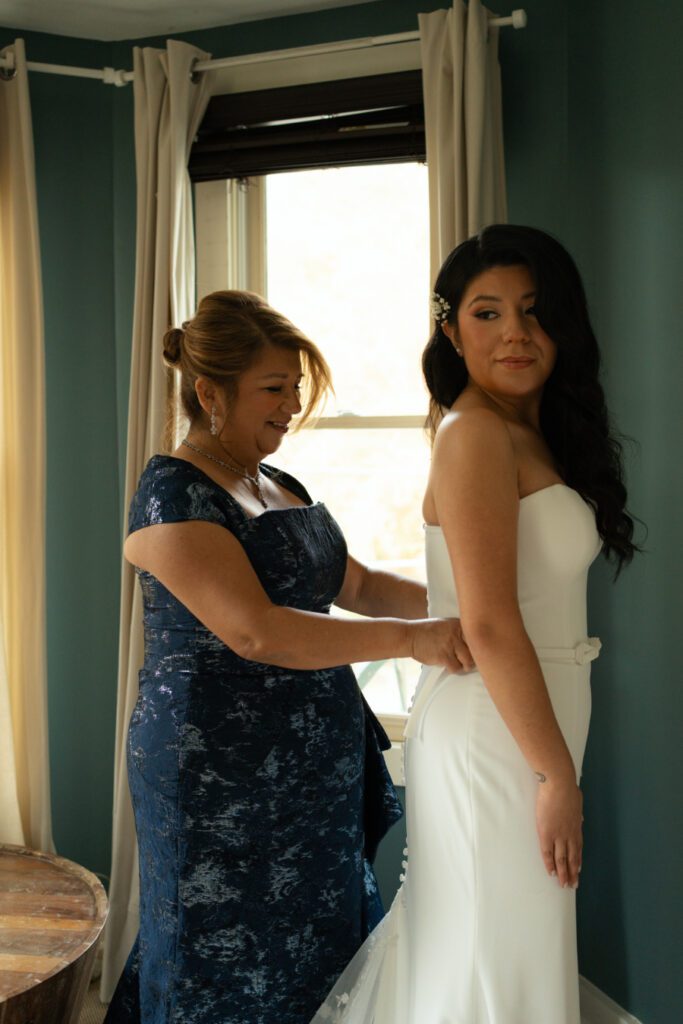 brides mother helping bride with her dress