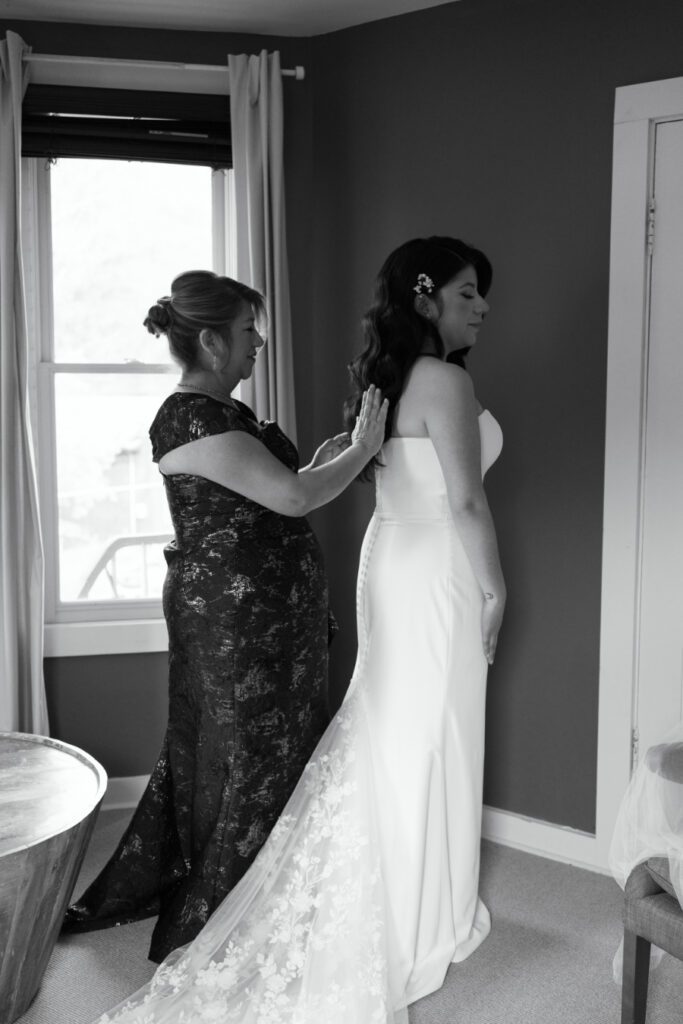 brides mother helping bride with her dress