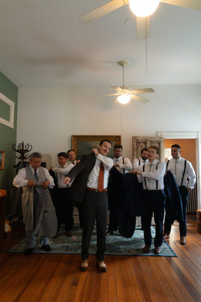 groom and groomsmen putting on their suit jackets