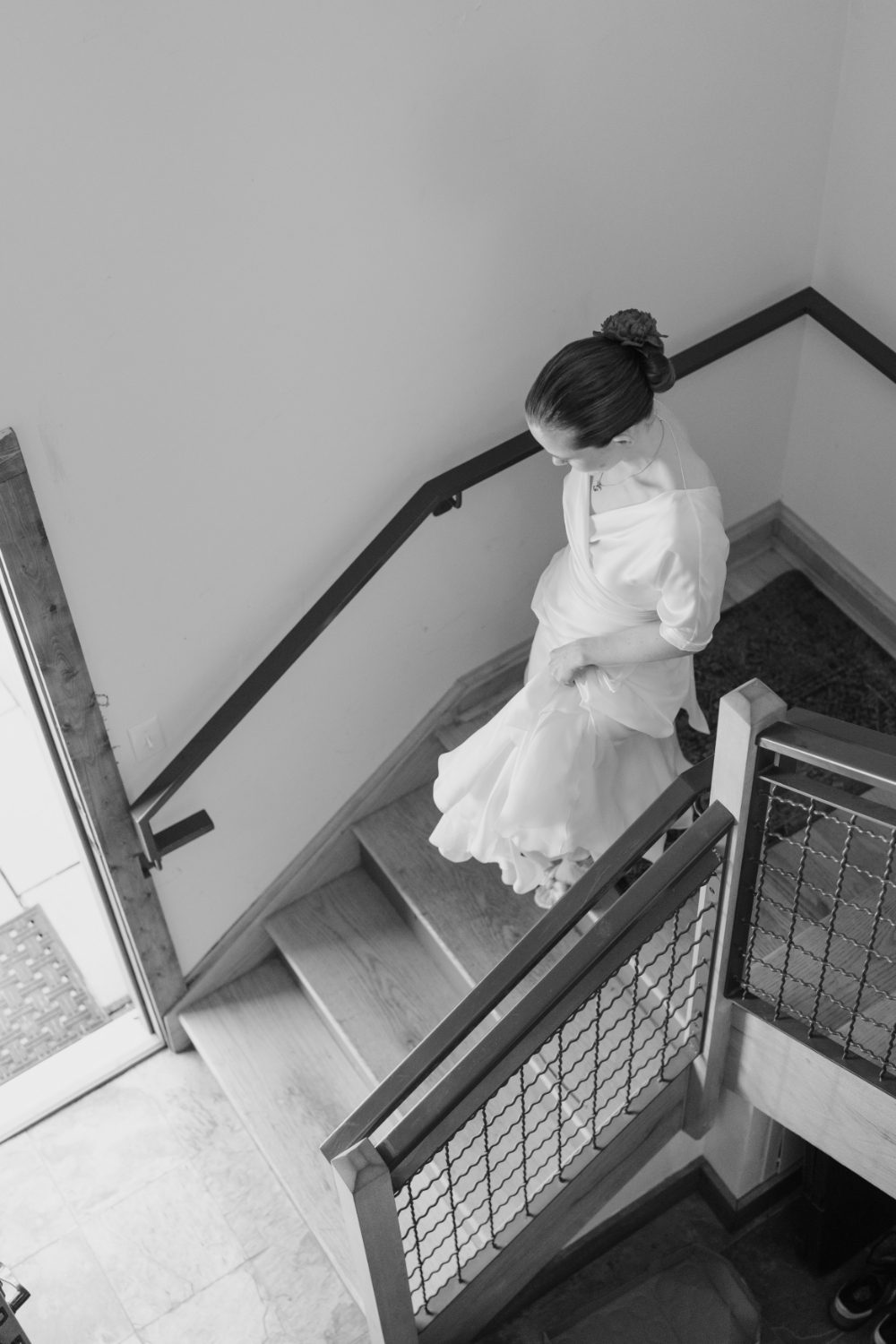 BLACK AND WHITE SHOT OF BRIDE DESCENDING STAIRS
