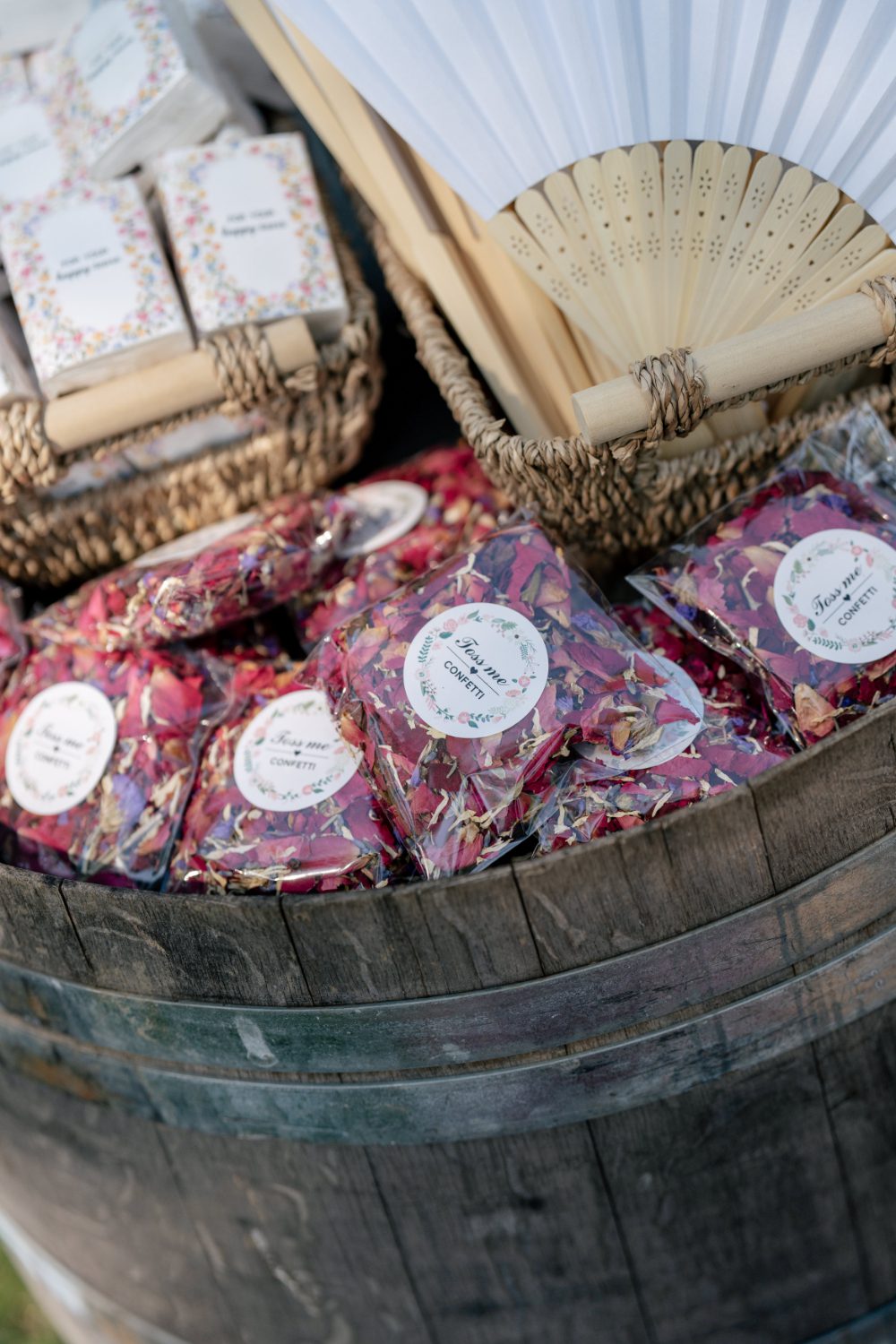 DRIED FLOWER CONFETTI, FANS, AND PROGRAMS INSIDE A BARREL FOR OUTDOOR WEDDING CEREMONY AT CITY WINERY HUDSON VALLEY