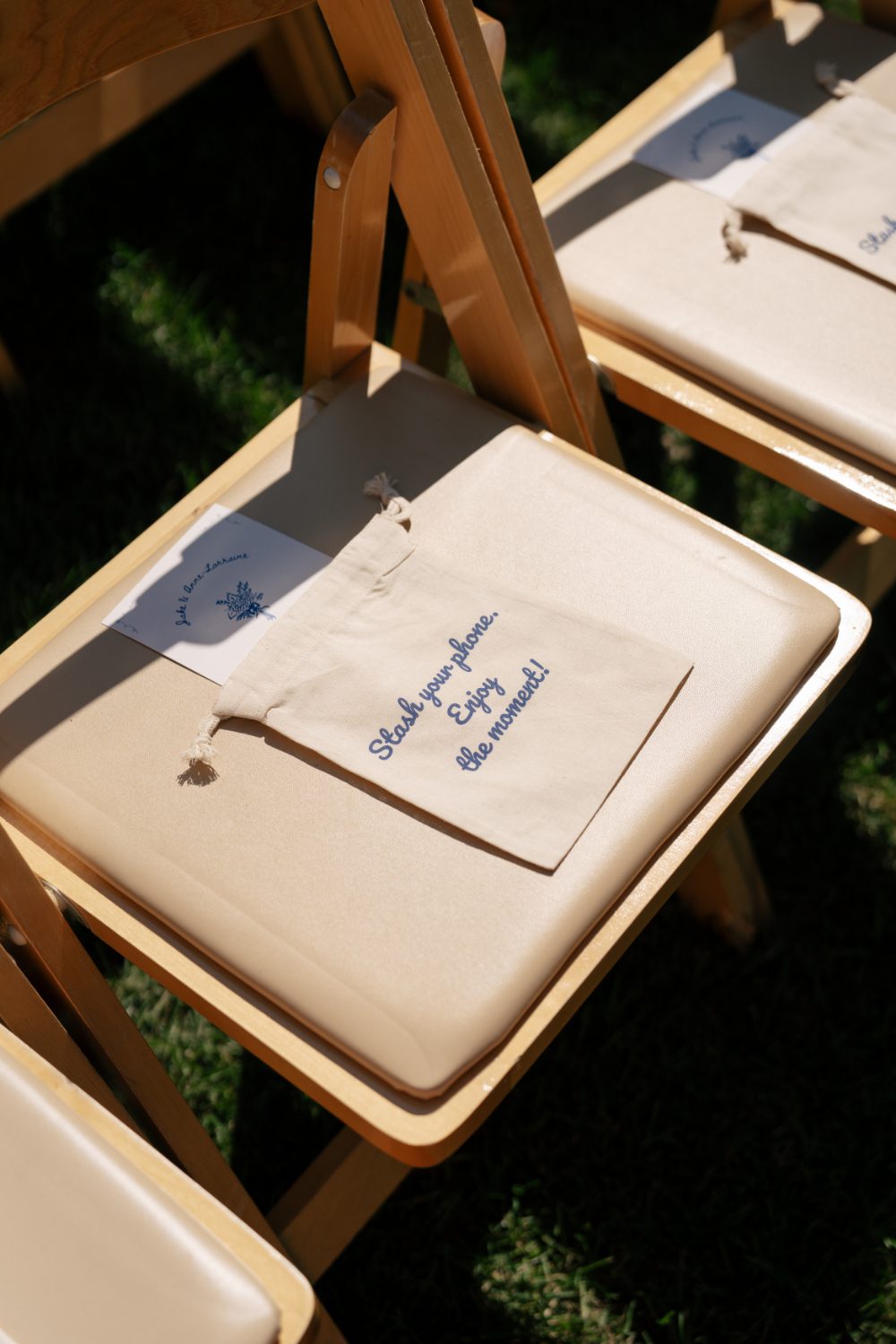 CLOSE UP OF WOODEN CEREMONY CHAIRS WITH PROGRAM AND A "UNPLUGGED CEREMONY" POUCH