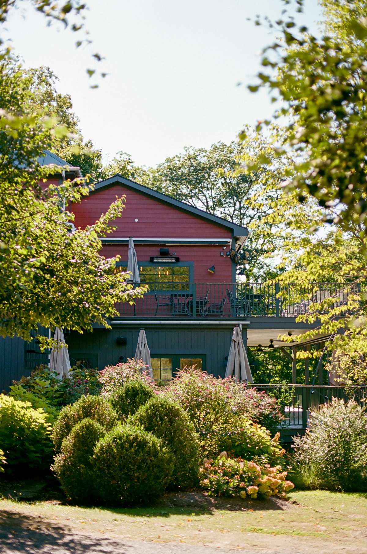 Charming red building at Buttermilk Falls with balconies, lush landscaping, and garden views, offering a peaceful backdrop for destination weddings in Hudson Valley.