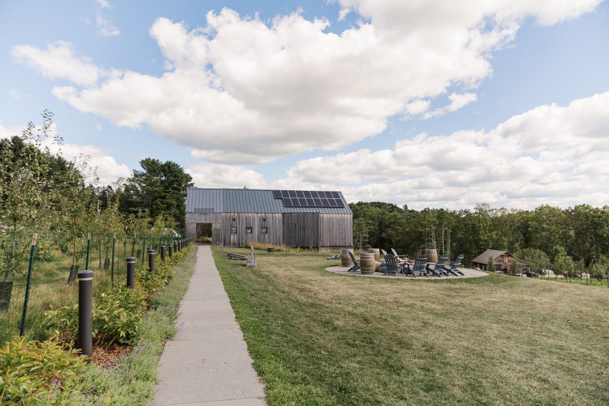 Scenic lawn at Seminary Hill featuring a modern barn, fire pit seating, and vineyard views, ideal for relaxed gatherings during destination weddings in Hudson Valley.