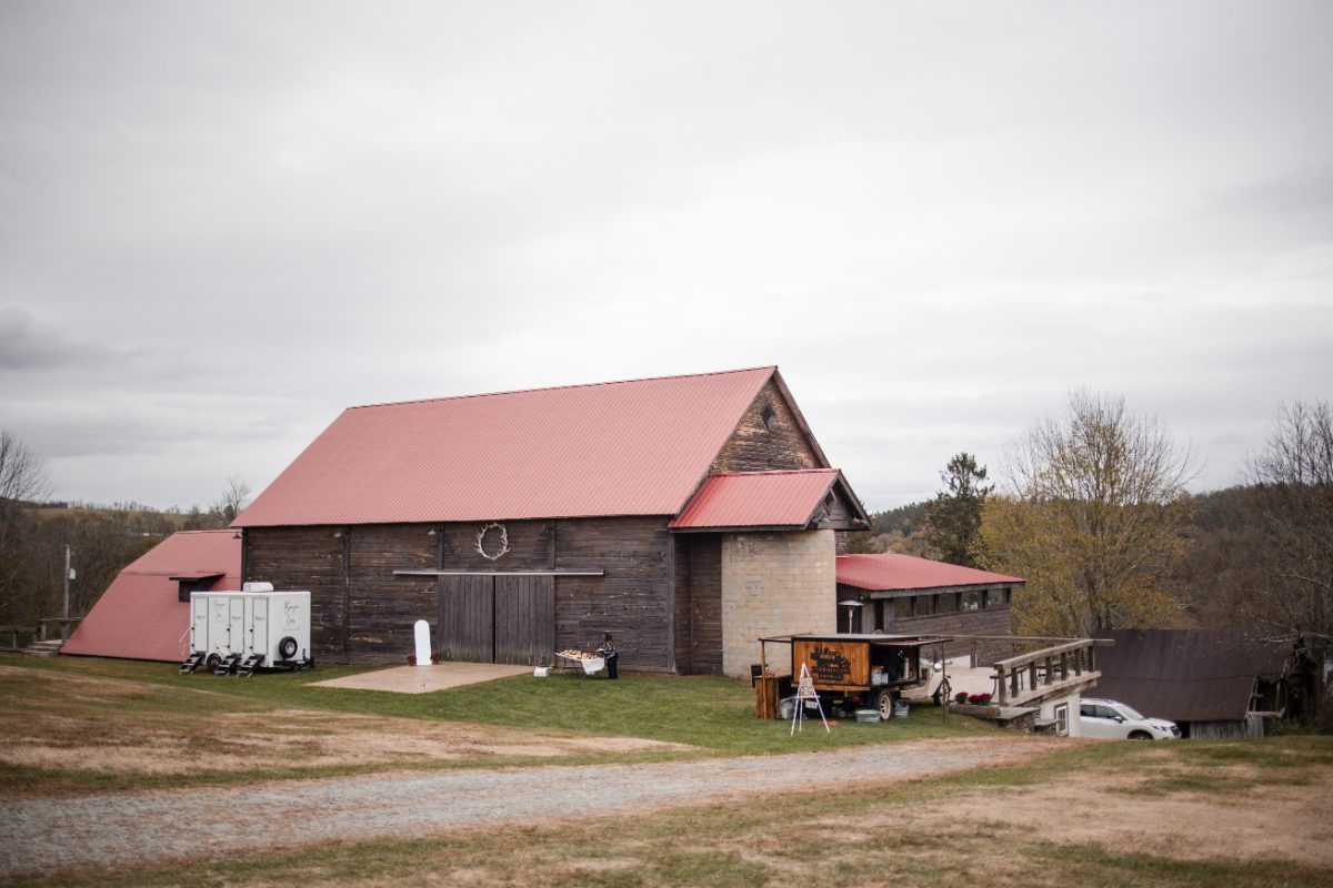 Exterior view of The Barn on Hubbard with weathered wood siding, red roofs, rolling grounds, and a quiet countryside setting for destination weddings in Hudson Valley.