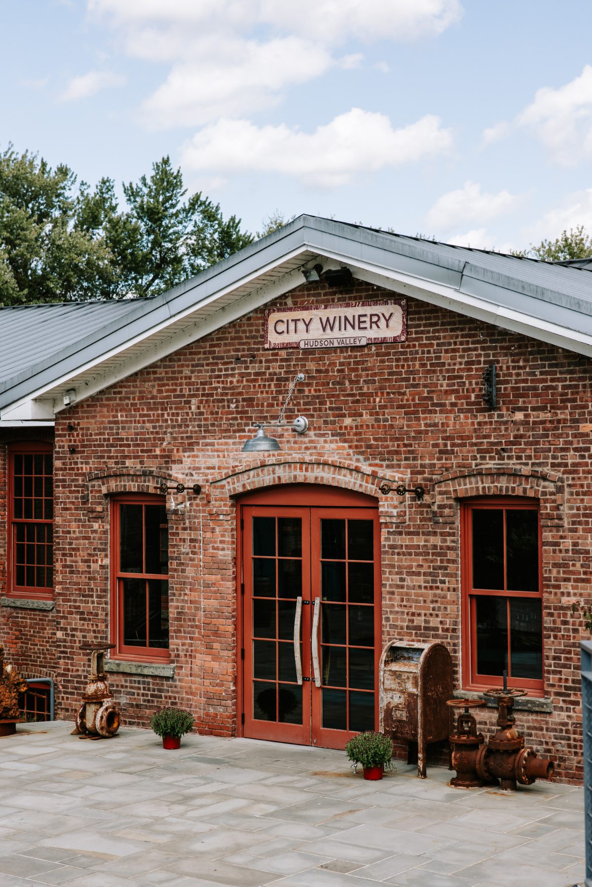 Front entrance of City Winery Hudson Valley featuring red-framed doors, exposed brick, and industrial details, blending historic charm with modern design for destination weddings in Hudson Valley.
