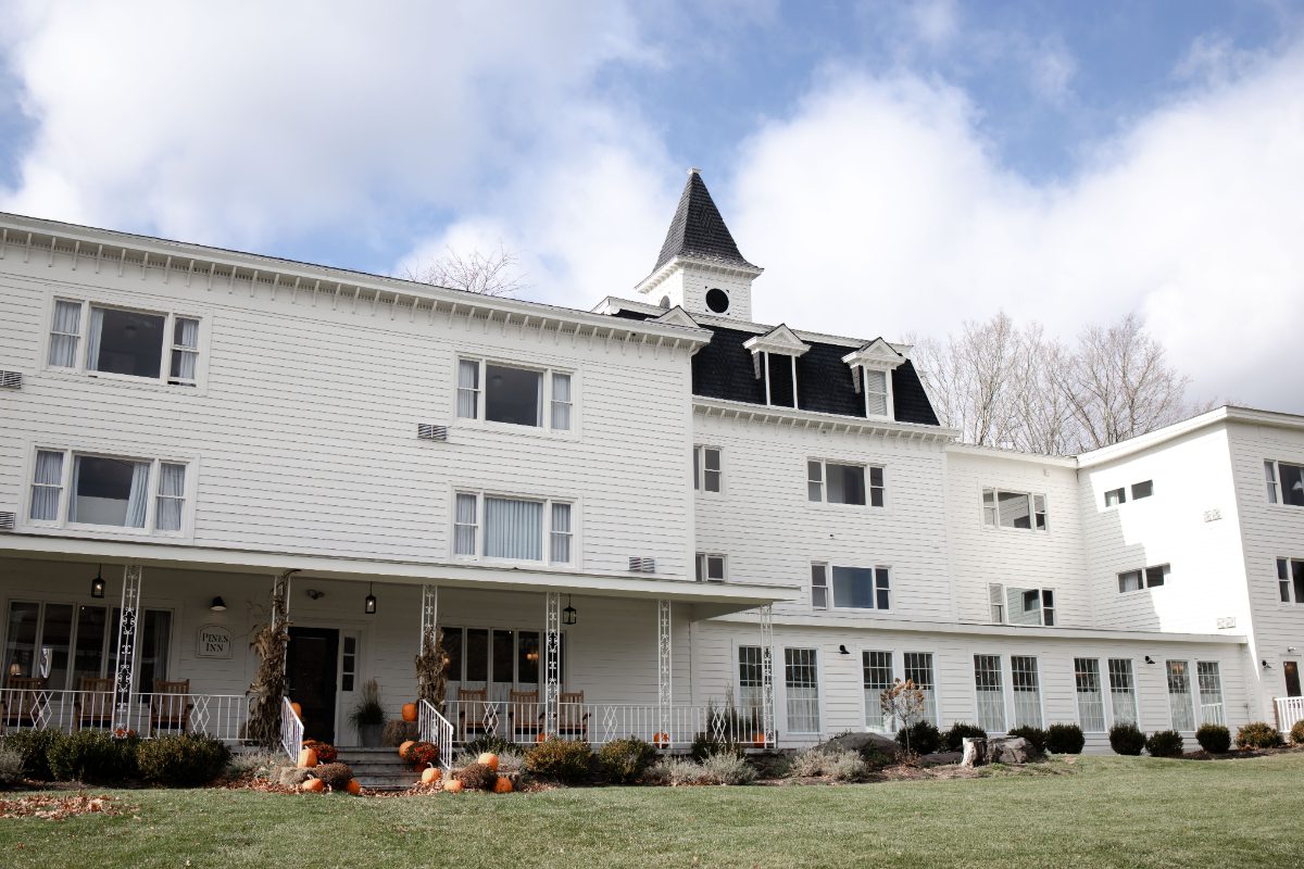 Historic white inn at Wylder at Windham with classic architecture, wraparound porch, and seasonal decor, offering charming accommodations for destination weddings in Hudson Valley.