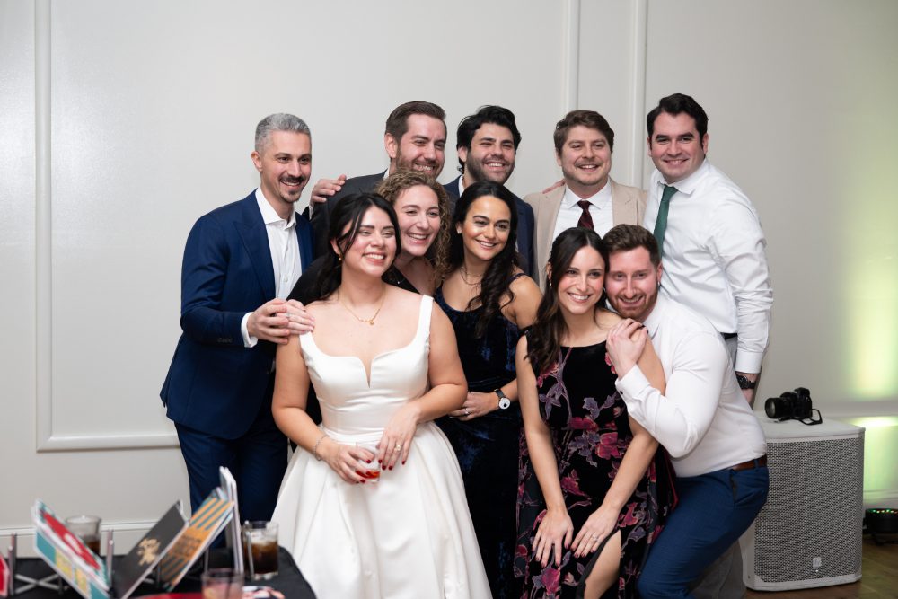 Bride smiles alongside friends for a group photo during her winter wedding reception at Audrey’s Farmhouse in the Hudson Valley.