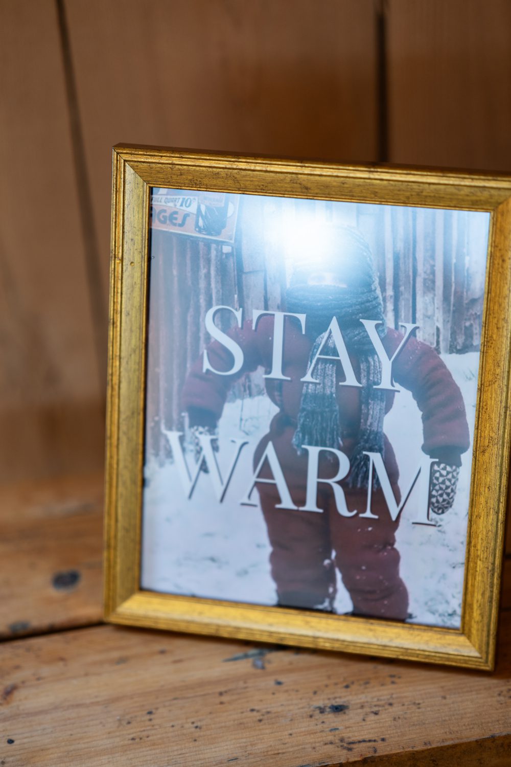 Gold-framed Stay Warm wedding sign featuring a personal winter photograph at Emma and Evan’s wedding.