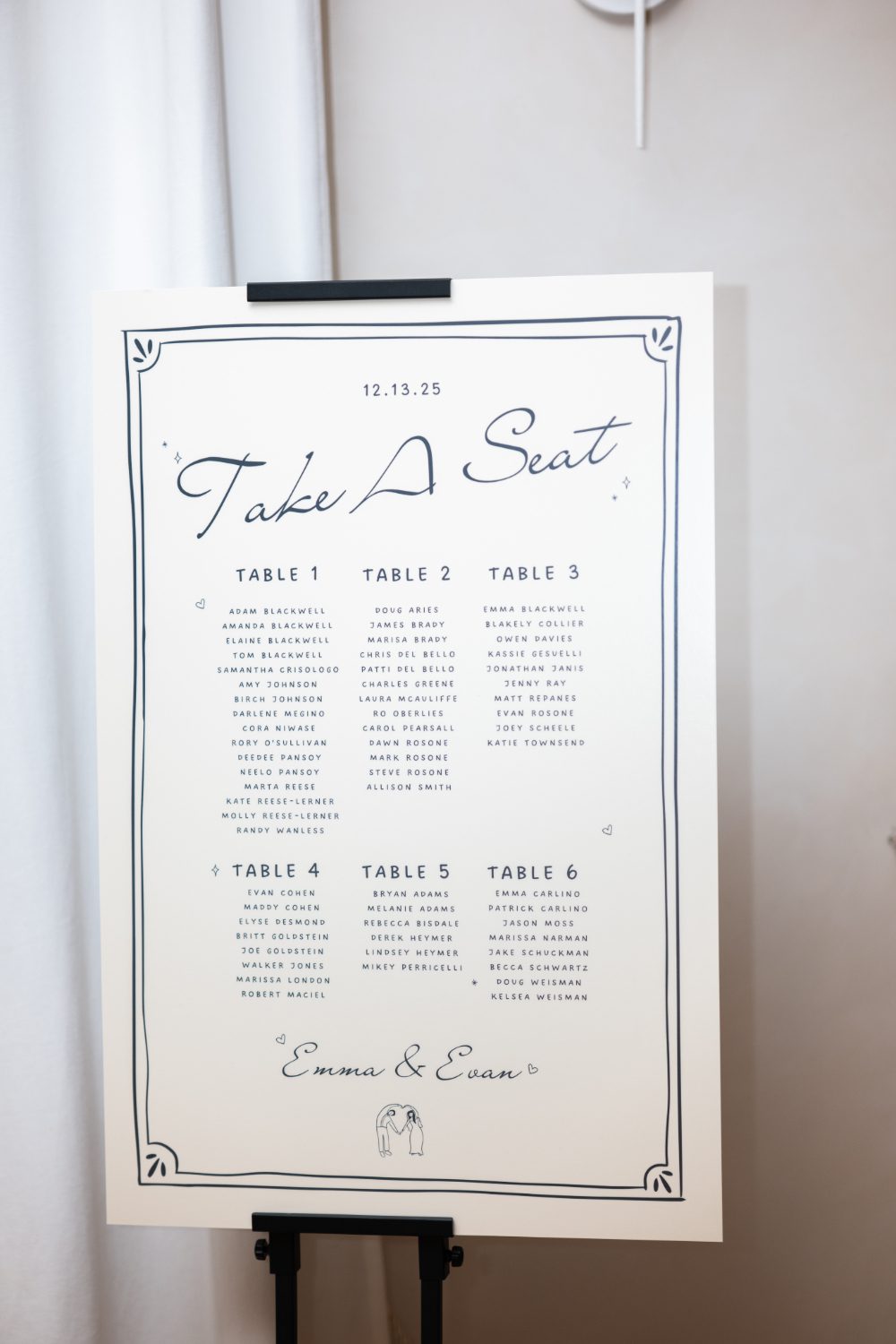Personalized wedding seating chart with elegant blue lettering and hand-drawn details for Emma and Evan’s December wedding.